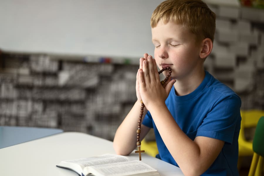 niño orando con biblia